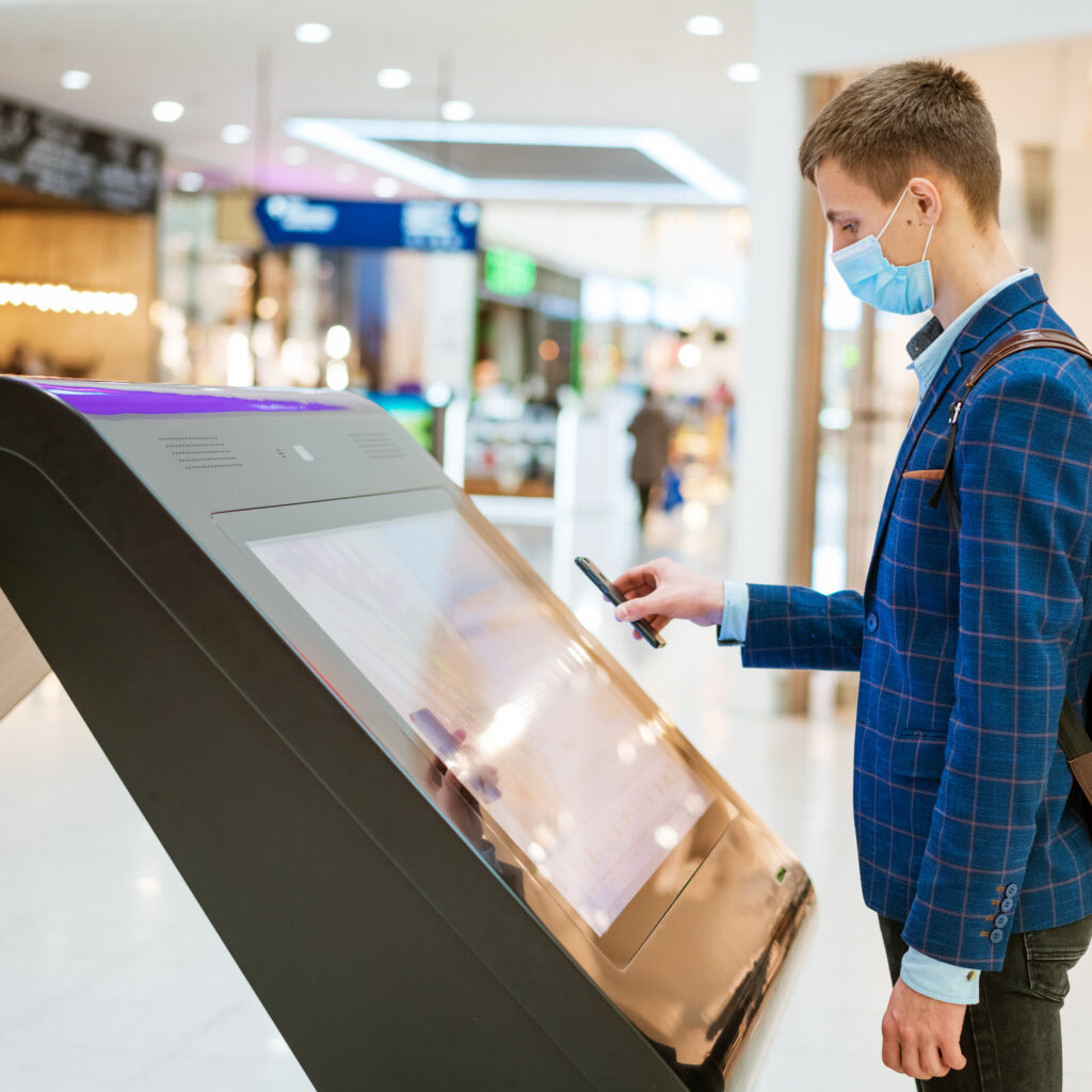 young man in a shopping mall looks at the monitor in a mask, the concept of internet search